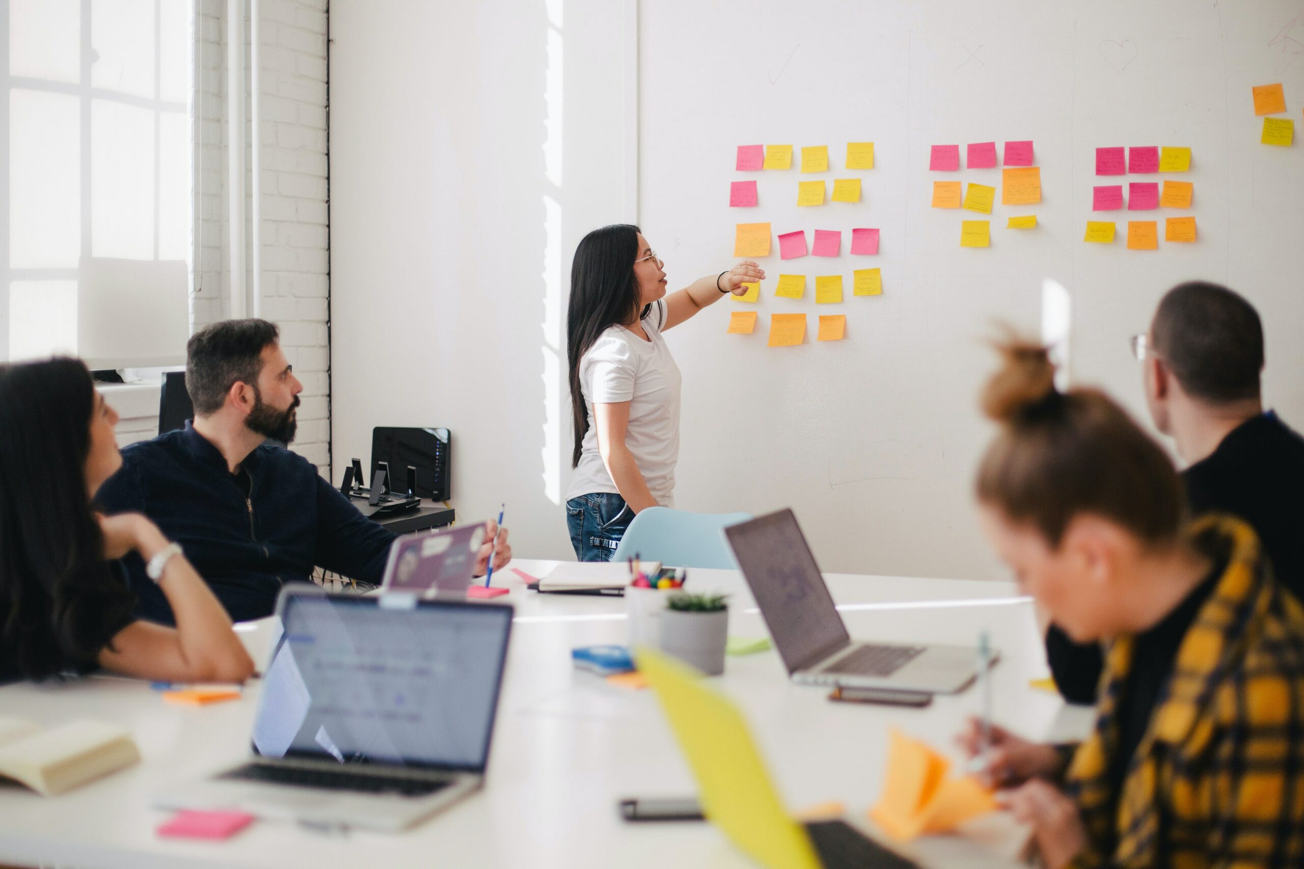 Femme plaçant des posts-its sur un mur © Jason Goodman/Unsplash 